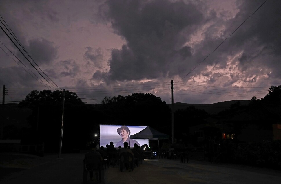 경남 거창군 웅양면 동호마을 들머리에 설치된 대형 스크린에 한국영상자료원 ‘찾아가는 영화관’이 <위험한 상견례 2>을 상영했다. 영화 상영 중 마른번개가 쳐서 하늘이 순간 환해졌다.