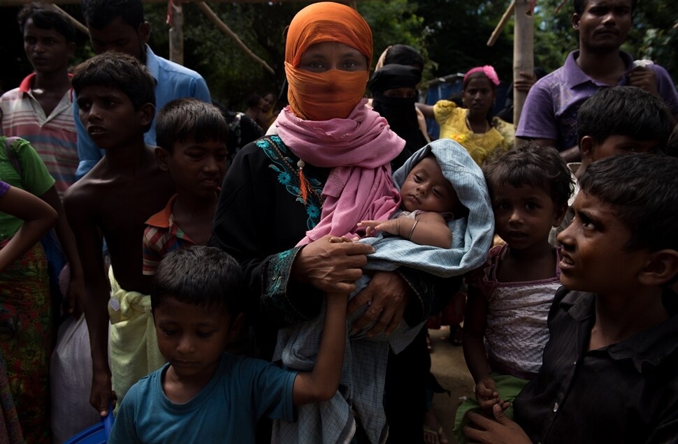 10월13일 방글라데시로 도망 나온 로힝야 가족이 서류 작성과 간단한 의료 검사를 받기 위해 나무 그늘에서 기다리고 있다. 이런 로힝야의 80%가 여성과 어린이다.