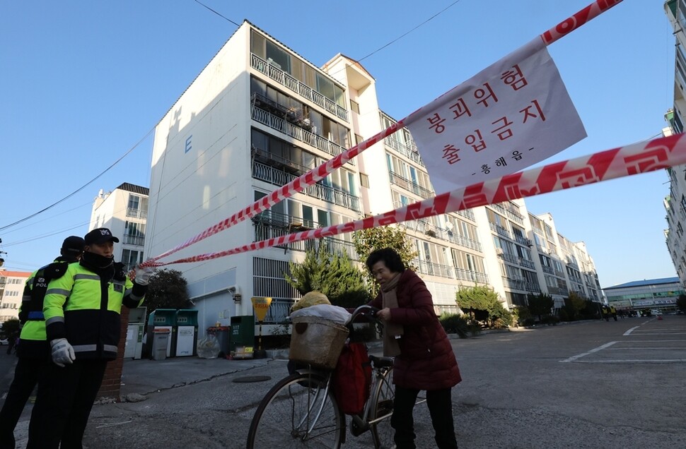 지진으로 파손된 아파트에서 주민이 자전거에 살림살이를 챙겨 나오고 있다. 이 아파트는 벽에 균열이 생기고 기둥이 파손돼 옆으로 기울어졌다. 아파트에는 사람의 출입이 금지됐다.