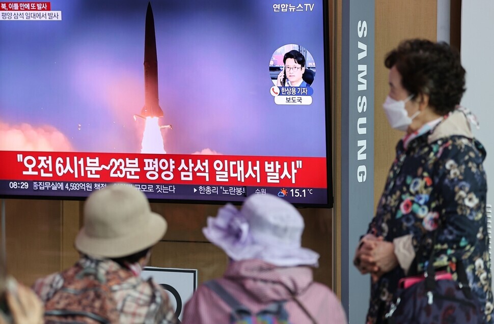 Travelers passing through Seoul Station watch a news report on recent missile tests by North Korea on Oct. 7. (Yonhap)