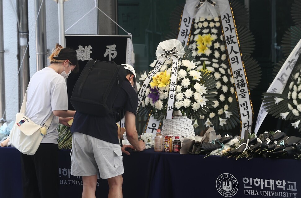Two people write notes on July 17 at a memorial on the Inha University campus for a young woman who died after being sexually assaulted on campus. (Yoon Woon-sik/The Hankyoreh)
