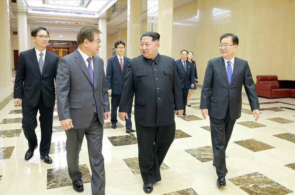A photo from the front page of the Mar. 6 edition of Rodong Shimun shows North Korean leader Kim Jong-un walking with members of South Korea’s special delegation and speaking to NIS Director Suh Hoon. (Yonhap News)