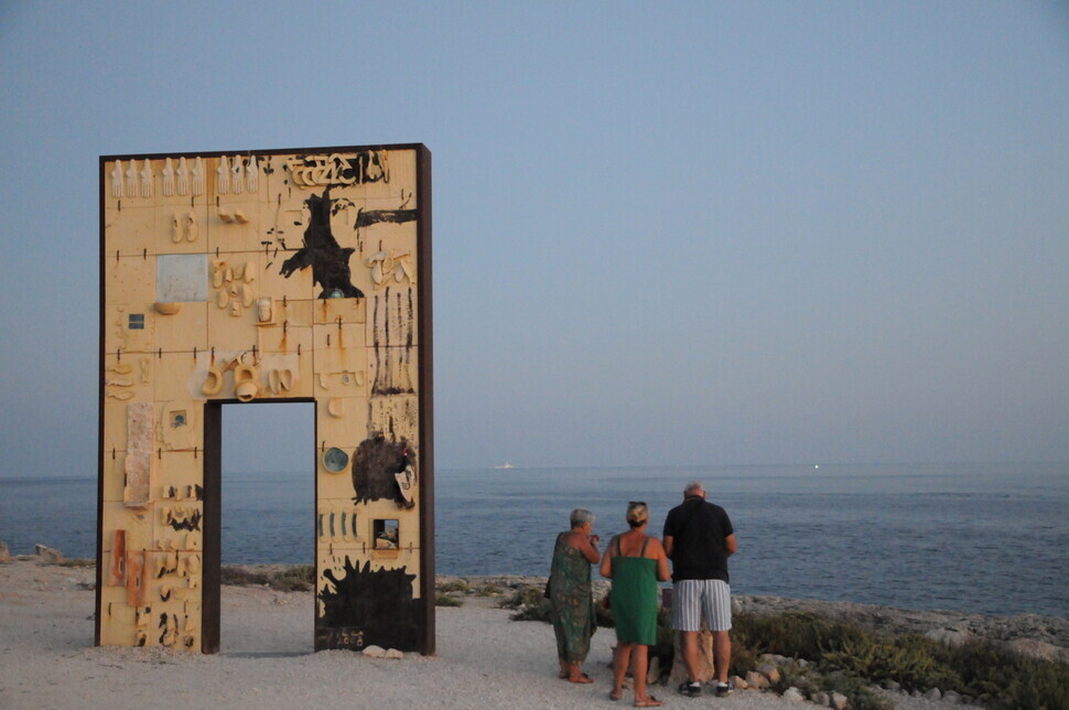 People stand near the “Gateway to Europe” on the Italian island of Lampedusa on Oct. 3. (Noh Ji-won/The Hankyoreh)