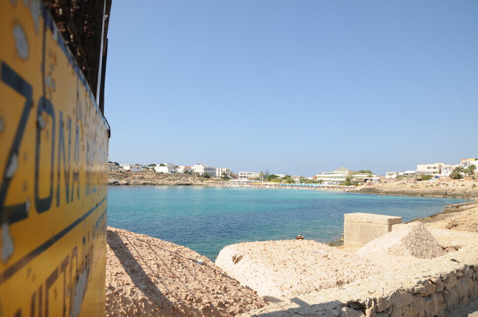 Around 11 am on Oct. 4, a boat full of migrants that set off from Tunisia arrived at the Favaloro Pier on Lampedusa. At the beach down the shore from the pier, tourists can be seen swimming and sunbathing. (Noh Ji-won/The Hankyoreh)