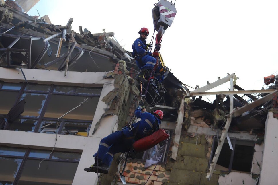 Equipes de resgate e paramédicos fazem buscas no local de um complexo residencial e comercial em Kiiu, capital da Ucrânia, que foi atacado pelas forças russas no dia 26 (horário local).  Um telegrama oficial foi fornecido à cidade de Kyuu
