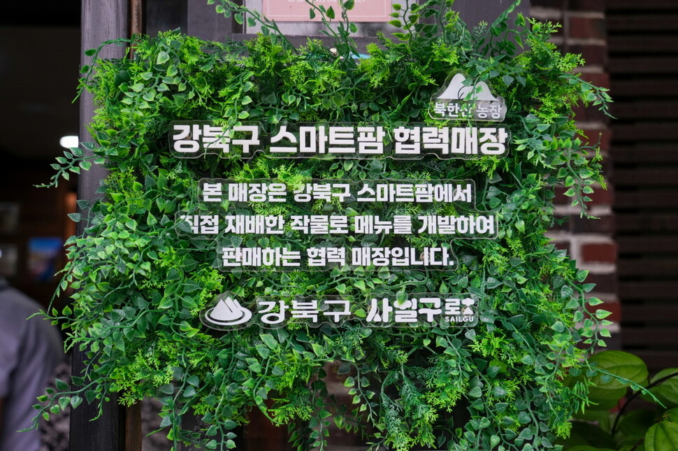 서울 강북구 수유동 4·19 카페거리의 ‘까미노빵집’ ‘4.19국수김밥’ 등 8개 협력매장이 강북 스마트팜에서 재배한 루꼴라와 애플 수박 등을 활용한 시그니처 메뉴를 선보이고 있다. 사진은 협력매장 입구에 적힌 안내문. 강북구청 제공