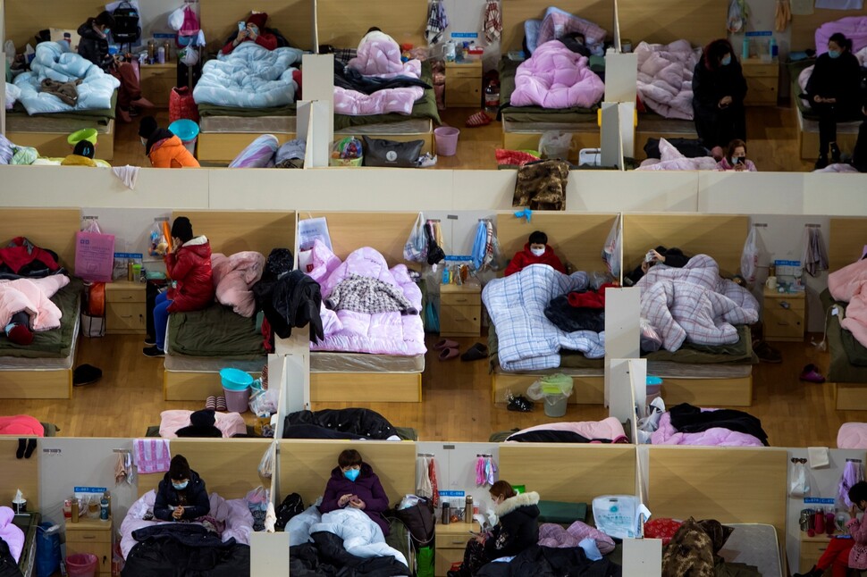 중국 후베이성 우한의 우한스포츠센터에 마련된 임시병동에서 2월17일 코로나19 확진자들이 집단생활을 하고 있다. 확진자 수천 명을 수용하려다보니 얄팍한 간이 칸막이에, 그마저도 여러 명이 한 공간에서 지내고 있다.