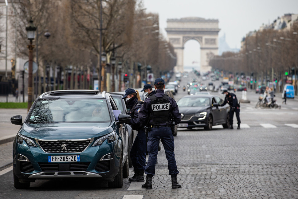 Police officers question commuters in Paris’ Avenue des Champs-Élysées on Mar. 17, when everyone in France was ordered to stay home and avoid going outside unless absolutely necessary. (Yonhap News)