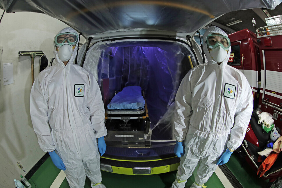 Emergency response workers finishing prepping an ambulance for transporting a COVID-19 by covering the inside of the vehicle with a special protective film. (Kim Myoung-jin, staff photographer)