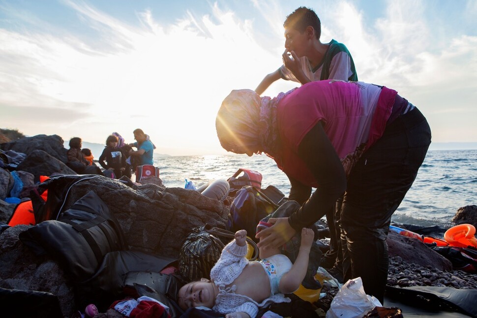 시리아 난민 여성이 유럽의 첫 관문인 그리스 레스보스 섬에 도착하자마자 아기의 기저귀를 갈아주고 있다. 레스보스, 그리스. 2016년 9월