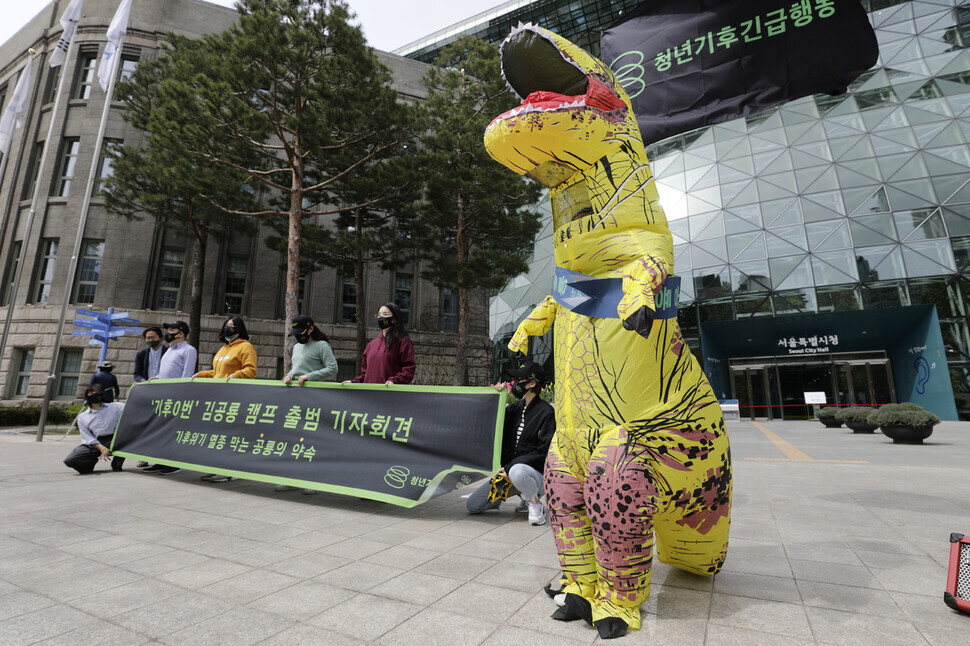 A member of the group Youth Climate Emergency Action announces climate policy proposals Thursday in front of Seoul City Hall while dressed in a dinosaur costume as 
