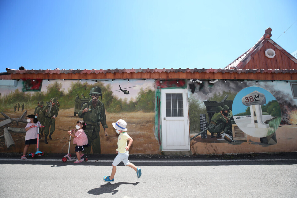 Children run in front of a mural in Kisamun Village next to Jangyo Village. (Baek So-ah/The Hankyoreh)
