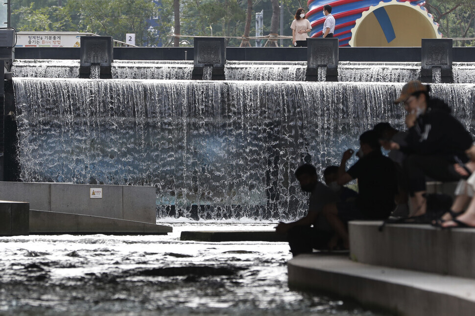Seoul residents avoid the heat at Cheonggye Stream on Monday, when the Korea Meteorological Administration issued heat advisories and warnings across South Korea. (Lee Jeong-a/The Hankyoreh)