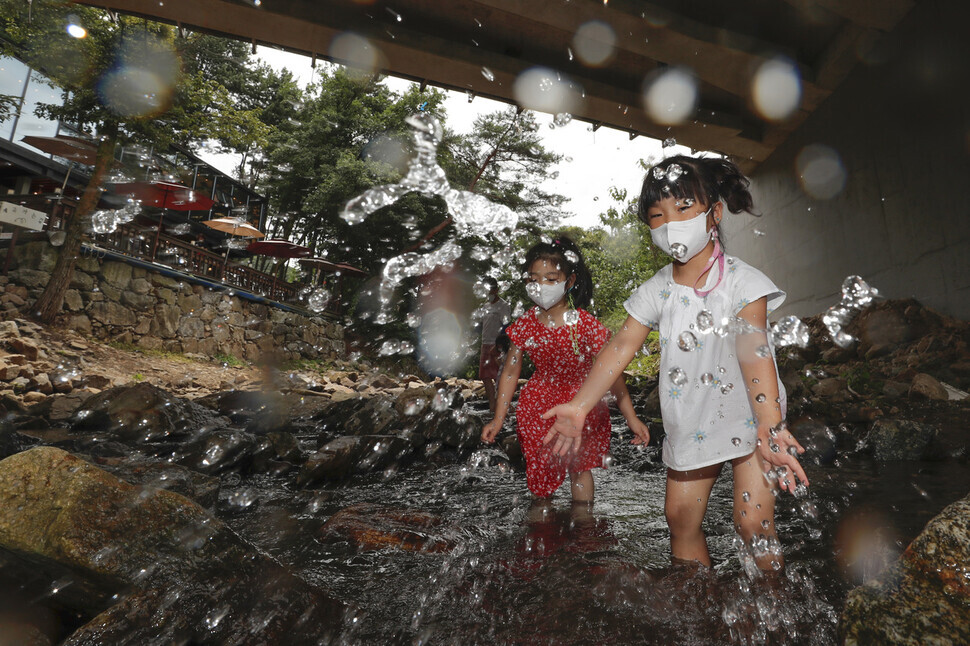 Two children play in the water at a stream in Yongin, Gyeonggi Province, on Tuesday. (Lee Jeong-a/The Hankyoreh)