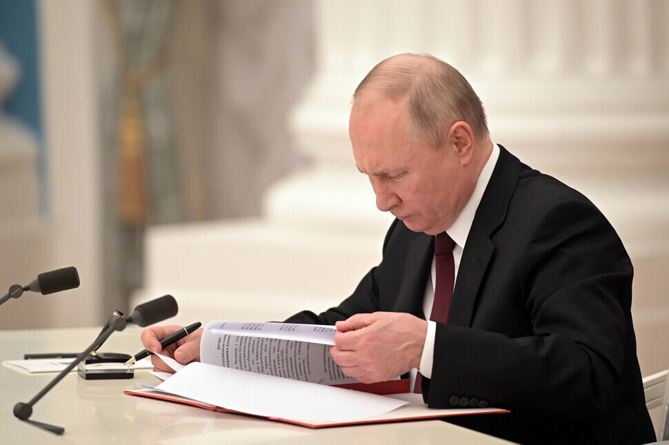 Russian President Vladimir Putin signs documents, including a decree recognizing two Russian-backed breakaway regions in eastern Ukraine as independent entities on Feb. 21, 2022. (TASS/Yonhap News)