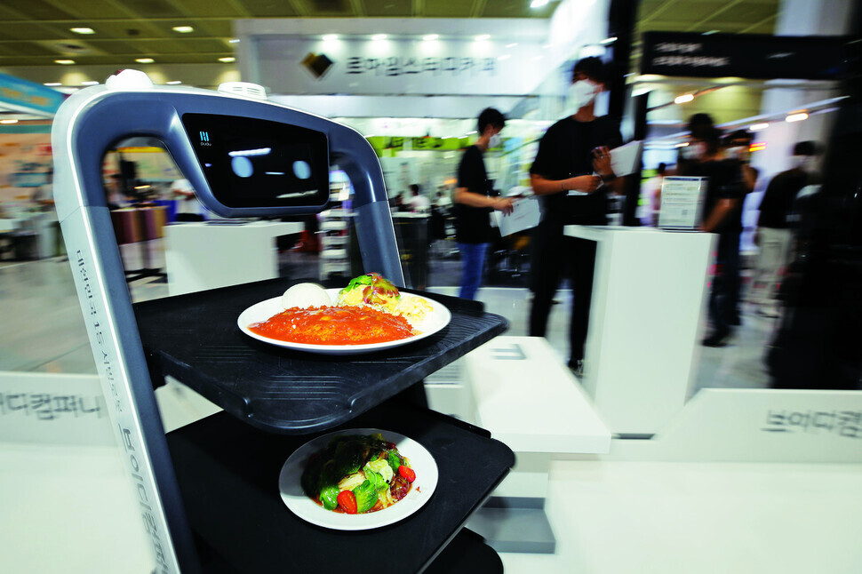 A smart conveyance robot demonstrates serving food at a booth at the 2021 International Franchise Show at Coex in Seoul. (Lee Jeong-a/The Hankyoreh)