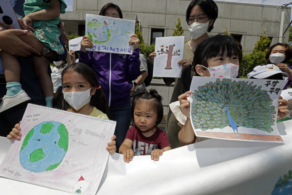 Children participating in the constitutional complaint hold up hand-drawn signs outside the Constitutional Court of Korea on June 13. (Kim Myoung-jin/The Hankyoreh)