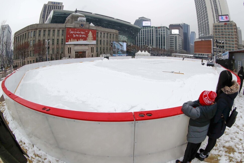 Passersby gaze at the ice rink in Seoul Plaza on Dec. 21, ahead of the rink opening for the first time in 3 years.