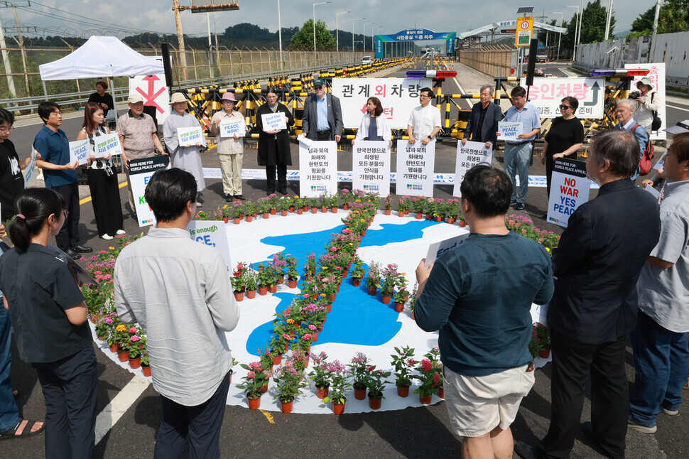 Participants in a press conference on a declaration of peace on the Korean Peninsula gather around a peace symbol made of flowers to remember those killed in the Korean War and pray for peace in Korea on July 27, the 70th anniversary of the armistice that paused the fighting of the Korean War. (Kim Hye-yun/The Hankyoreh)