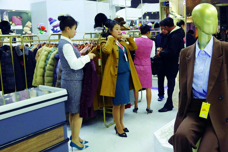 A woman tries on a jacket at an autumn garment fair held at Pyongyang’s Okryu Exhibition House on Nov. 9, 2023. (AP/Yonhap)