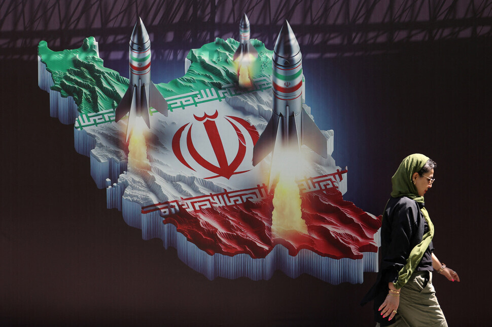 A woman walks by an anti-Israel banner in Tehran, Iran, depicting rocket launches on April 19, 2024. (Reuters/Yonhap)