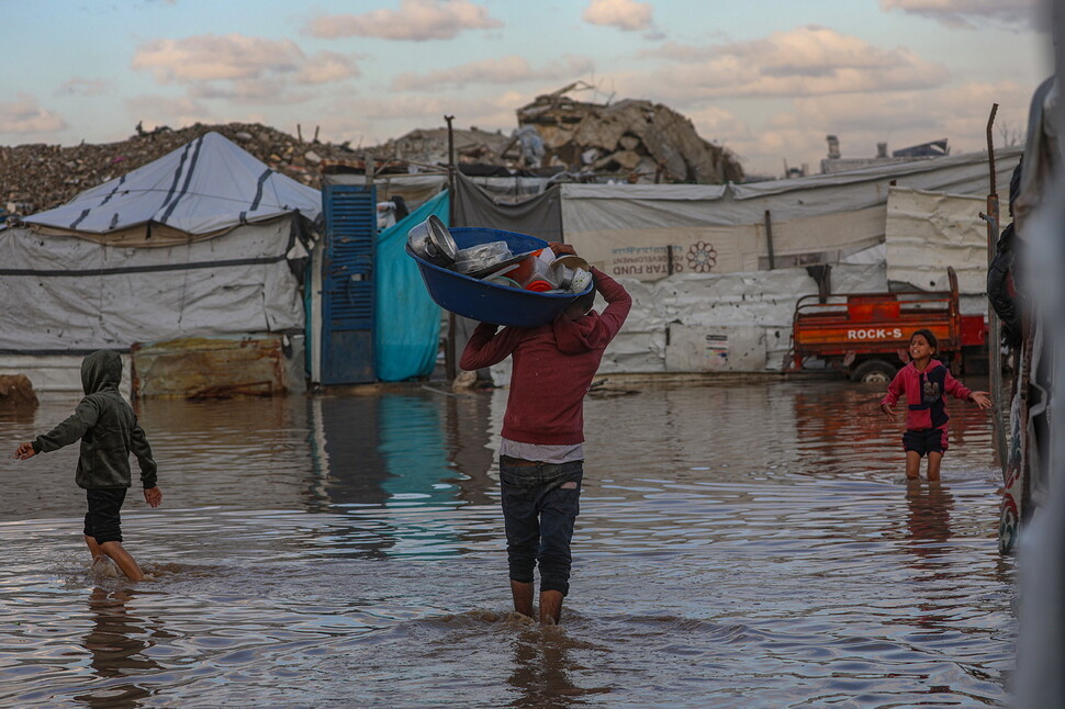 2025년 11월25일 폭우로 침수된 팔레스타인 땅 가자지구 북부 가자시티 외곽 자이툰에서 한 피란민이 가재도구를 바구니에 담아 옮기고 있다. EPA 연합뉴스