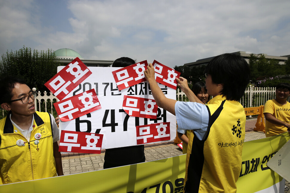 Members of a labor union put stickers with the word “invalid” on a signboard with “6