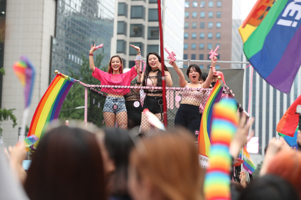 Participants in the Queer Culture Festival wearing headbands with multicolored hearts smile at Seoul Plaza in front of City Hall