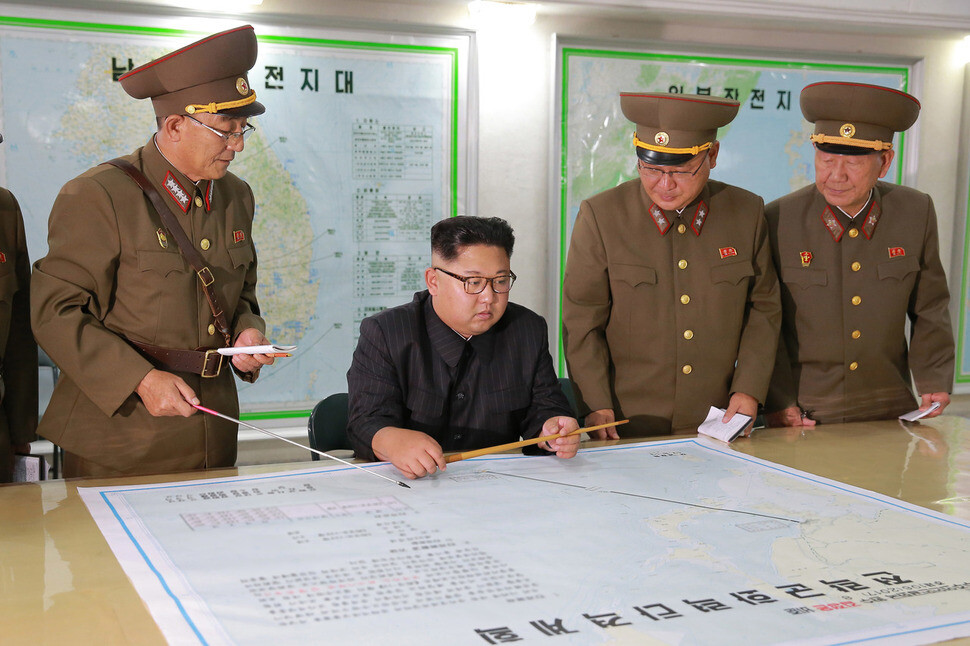 North Korean leader Kim Jong-un looks at an operational map for the “enveloping strike” on Guam at the Army Strategic Force command headquarters on Aug. 14.  The map shows a straight line from North Korea to the American territory of Guam.  (North Korean Central News Agency/Yonhap News)