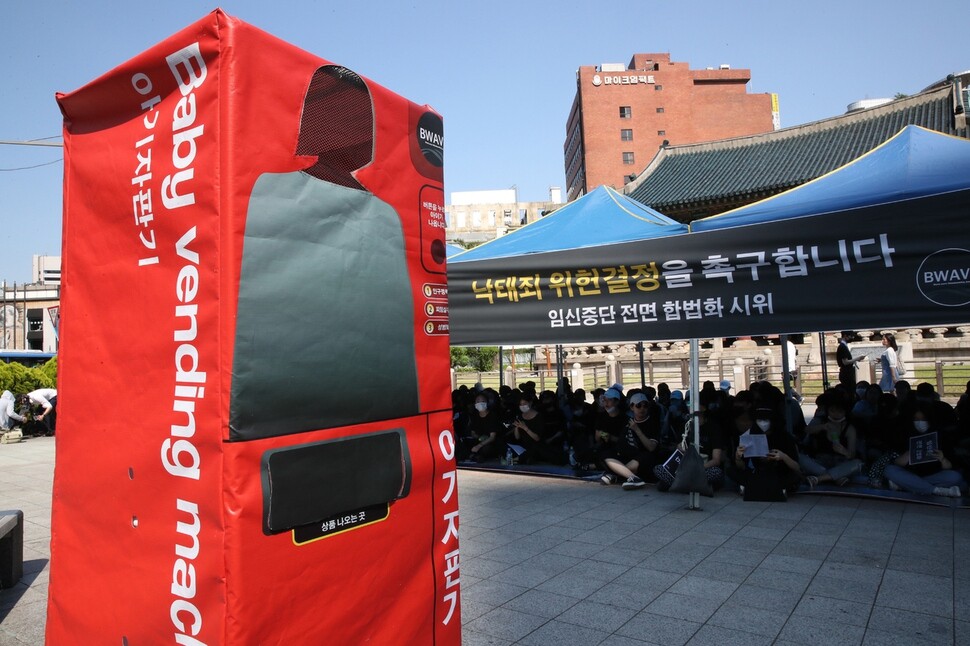 Members of the civic group BWAVE dressed in black and stood in front of the Bosingak belfry on June 3 to protest the criminalization of abortion. The group staged a “baby vending machine” performance to protest the perception of women as “baby factories.” (Kim Bong-gyu