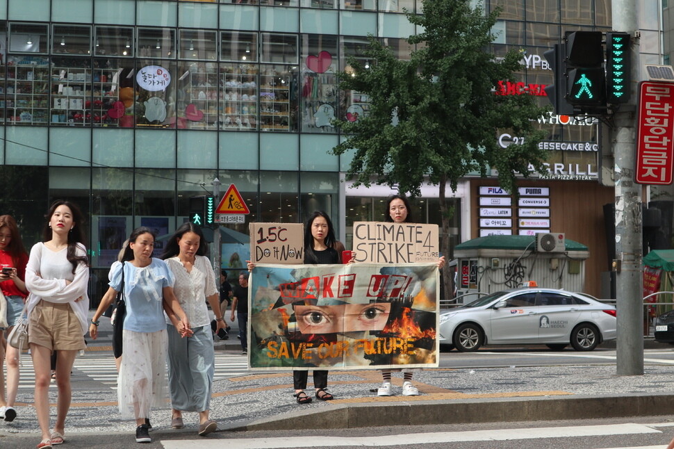 Oh Yeon-jae (left) and Kim Seo-gyeong (right) of the group Youth for Climate Action hold a demonstration regarding the severity of climate change in front of Hongik University Station in Seoul on Aug. 9. (provided by Youth for Climate Action)