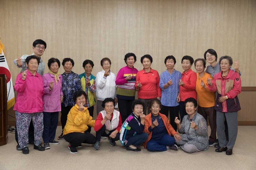 수업을 마친 할머니와 선생님들이 함께 손가락으로 하트를 만들어 보이고 있다.