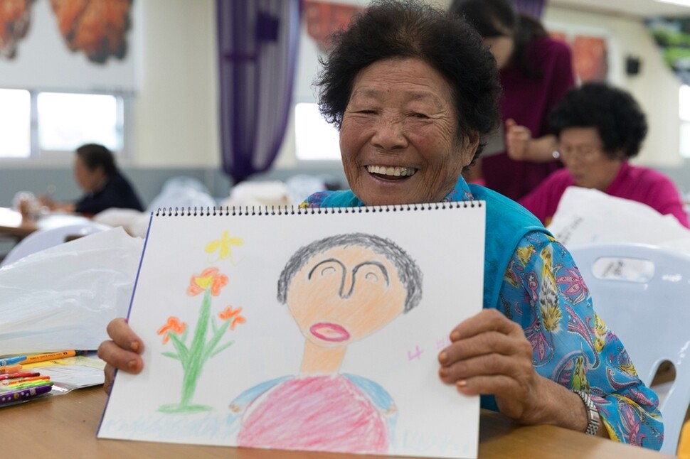 전남 장흥군 장평면에 사는 최복순 할머니가 9월26일 ‘자서전 쓰기’ 수업 중 직접 그린 자화상을 보여주며 쑥스러운 듯 웃고 있다.