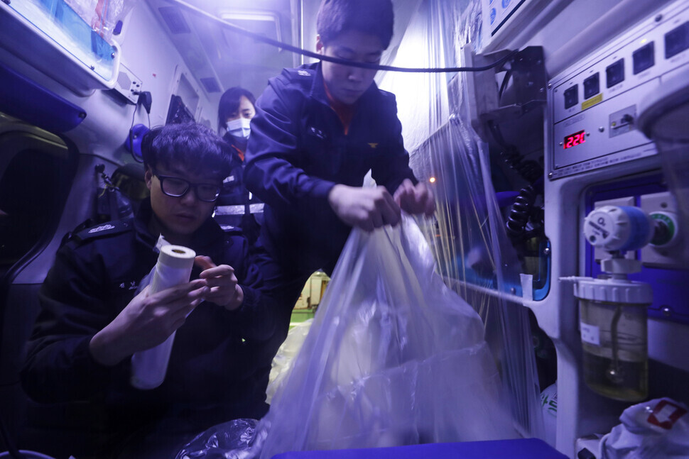 Emergency response workers cover the inside of an ambulance with a special protective film. (Kim Myoung-jin)