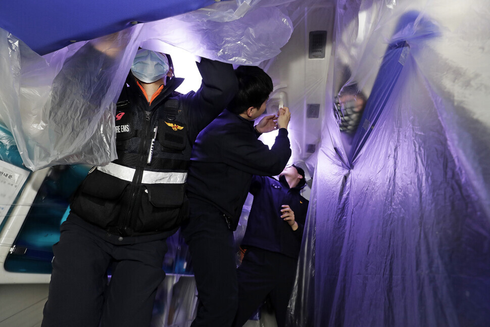 Emergency response workers cover the inside of an ambulance with a special protective film in the early hours of June 12. (Kim Myoung-jin)