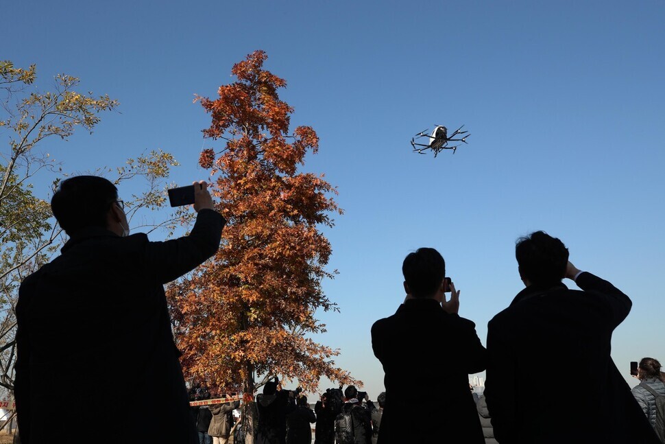 People snap photos of a drone during a test flight.