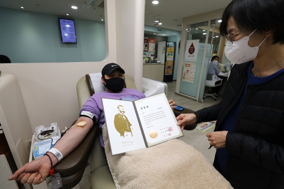 서른 번째 헌혈에 나선 이지훈(32)씨가 인정숙 간호사한테서 받은 헌혈 유공 포장증을 들어 보이고 있다.