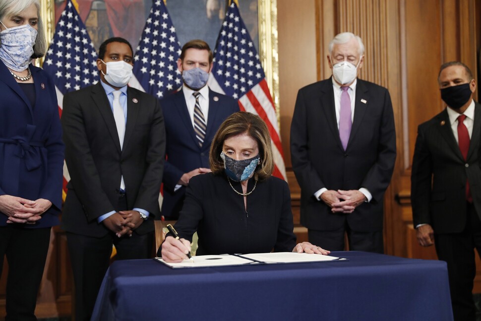 2021년 1월13일 오후(현지시각) 낸시 펠로시 미국 의회 하원의장(앞줄 테이블)이 표결로 채택된 도널드 트럼프 대통령의 탄핵소추안에 서명하고 있다. EPA 연합뉴스