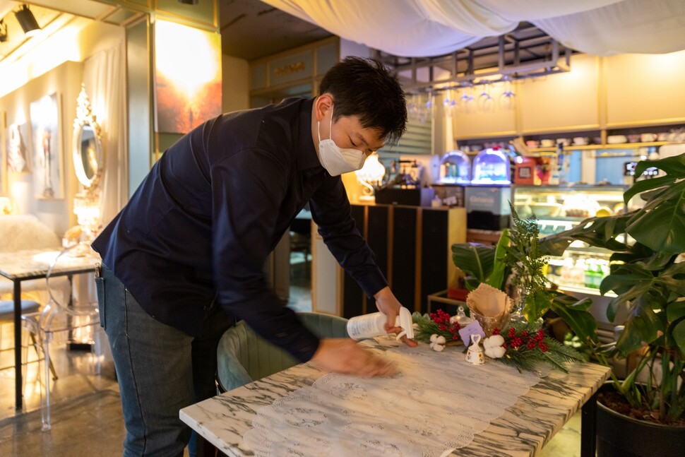 카페 ‘쉼’의 심혁 사장이 가게 탁자를 소독하고 있다.