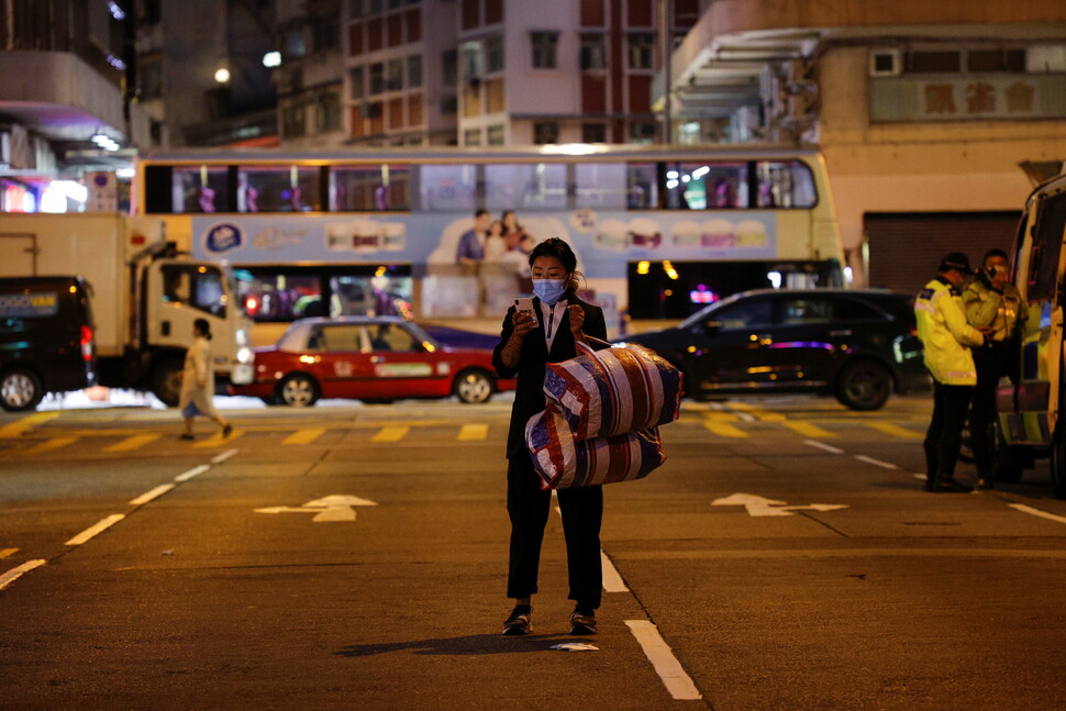 2021년 1월23일 홍콩 조던 지역이 코로나19 재확산으로 봉쇄된 가운데, 한 여성이 가방을 들고 발길을 옮기고 있다. 홍콩에서 코로나19 방역은 권위주의적 통제의 명분이 된다는 비판이 나온다. REUTERS 연합뉴스