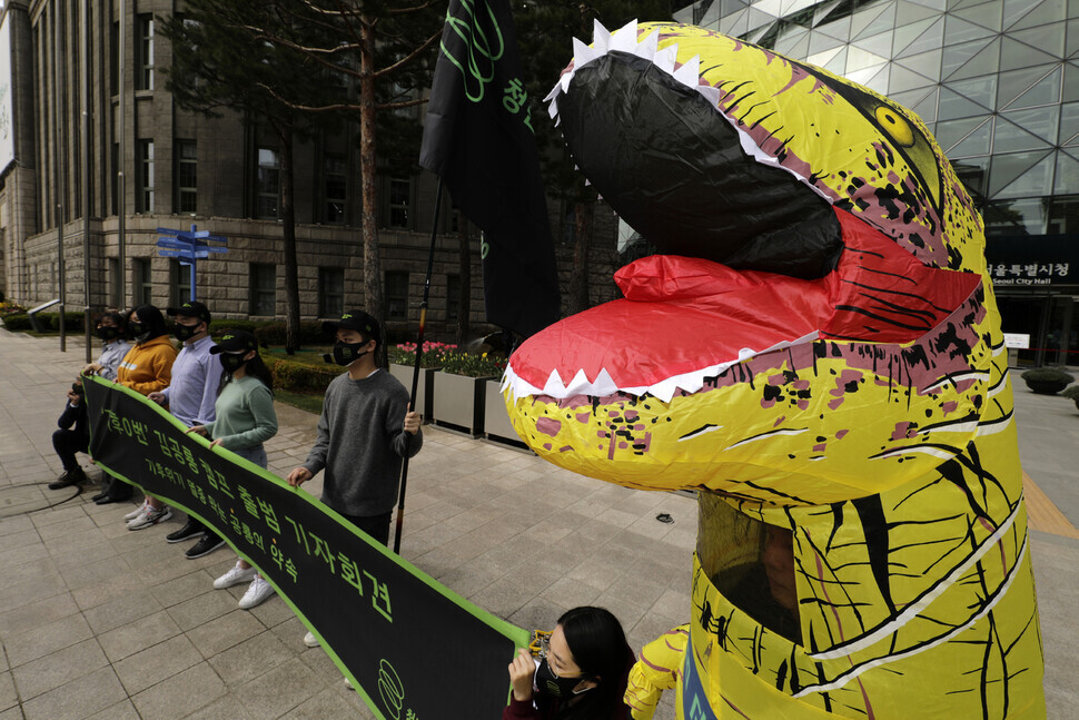 A member of the group Youth Climate Emergency Action announces climate policy proposals Thursday in front of Seoul City Hall while dressed in a dinosaur costume as 