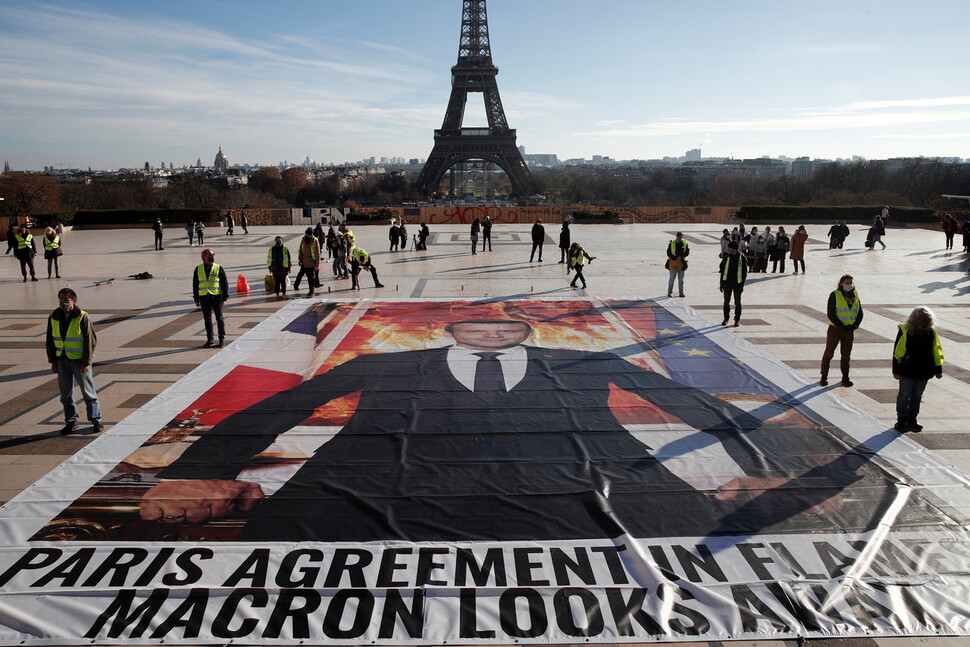 2021년 3월16일 프랑스 하원은 헌법 제1조에 ‘공화국은 생물다양성과 환경보존을 보장하고 기후변화에 맞서 싸워야 한다’는 문구를 담은 헌법개정안을 가결했다. 2020년 12월 파리에서 기후행동주의자들이 에마뉘엘 마크롱 프랑스 대통령의 대형 초상화를 에펠탑 앞 광장에 놓고 시위하고 있다. REUTERS