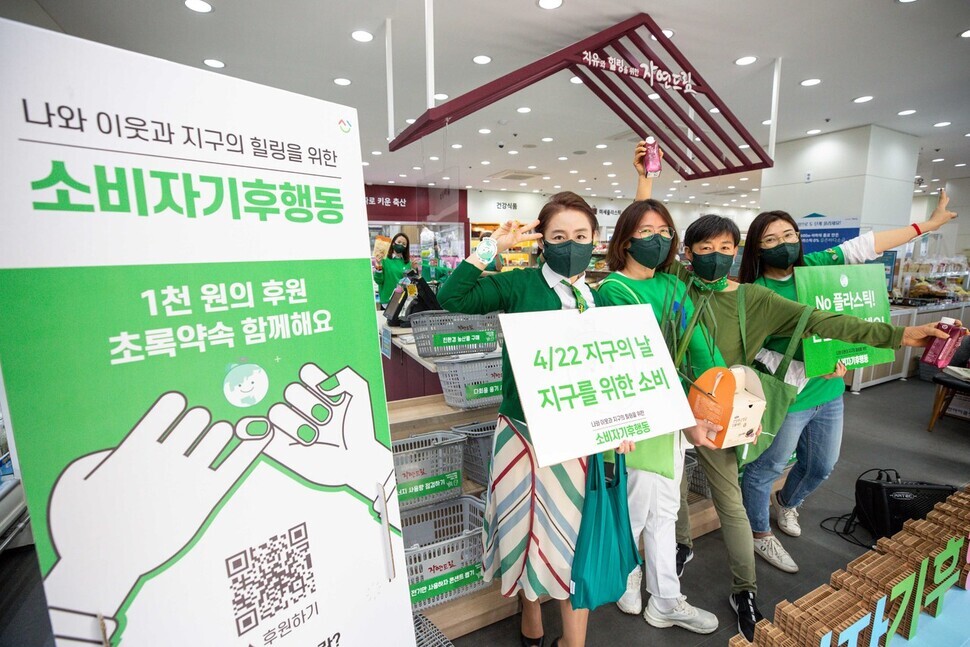 Members of Consumer Climate Action, dressed in green, ask consumers to buy eco-friendly food products and stop using plastic containers during the group’s event, titled “Code Green,” to mark the 51st Earth Day at the Mokdong branch of iCOOP Natural Dream store in Seoul. (pool photo)