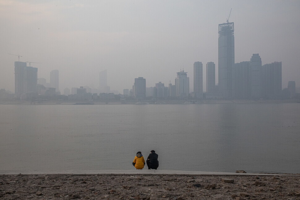 Two people sit on a riverbank in December 2020 while looking over the Yangtze River in Wuhan, China. (Yonhap News)