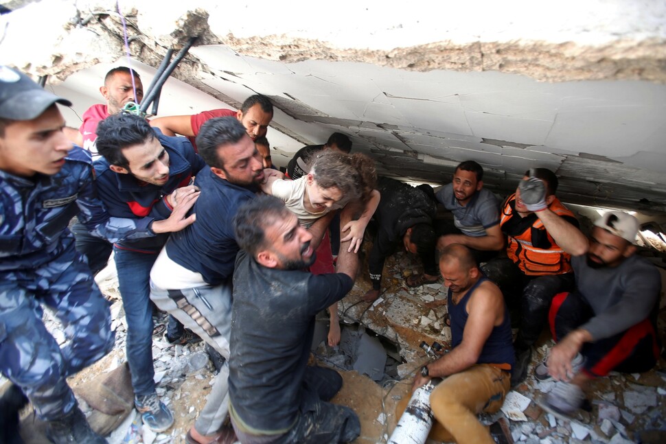 2021년 5월16일 이스라엘 전투기 폭격으로 붕괴된 팔레스타인 가자지구 리말의 한 건물 잔해 속에서 구조대원들이 6살 아이를 구출하고 있다. REUTERS