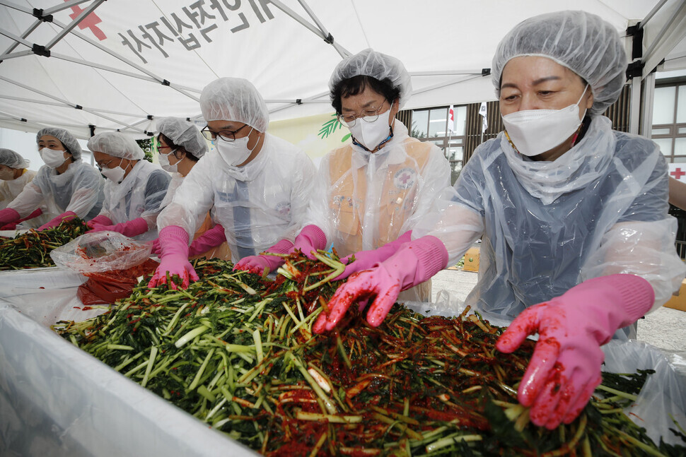 Red Cross volunteers mix young summer radishes soaked in salted water with red pepper powder and other seasonings on Thursday at the Korean Red Cross’ Nowon Ward in Seoul as they take part in a kimchi-making charity event. (Lee Jeong-a/The Hankyoreh)