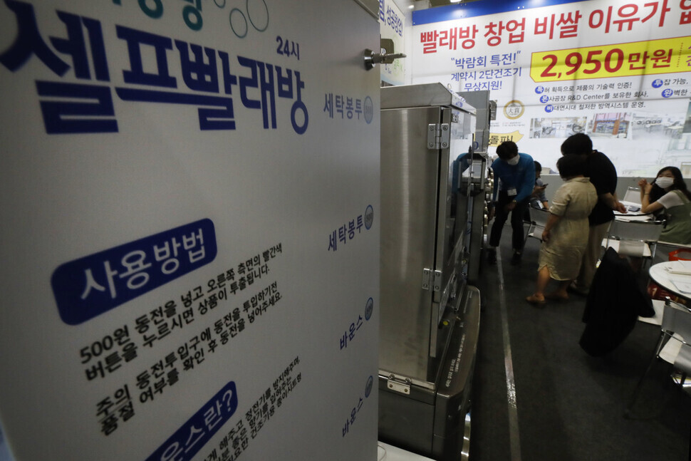 Visitors at the International Franchise Show held at Coex in Seoul talk to a representative at the booth for a self-service laundromat chain on Thursday. (Lee Jeong-a/The Hankyoreh)