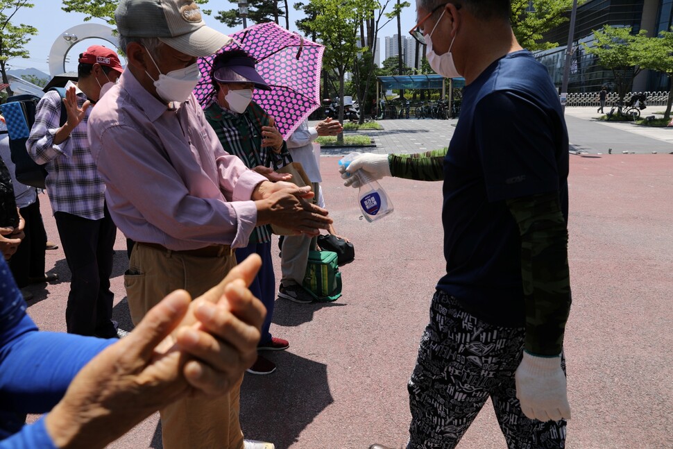 자원봉사자가 배식에 앞서 어르신들에게 손세정제를 뿌려주고 있다.