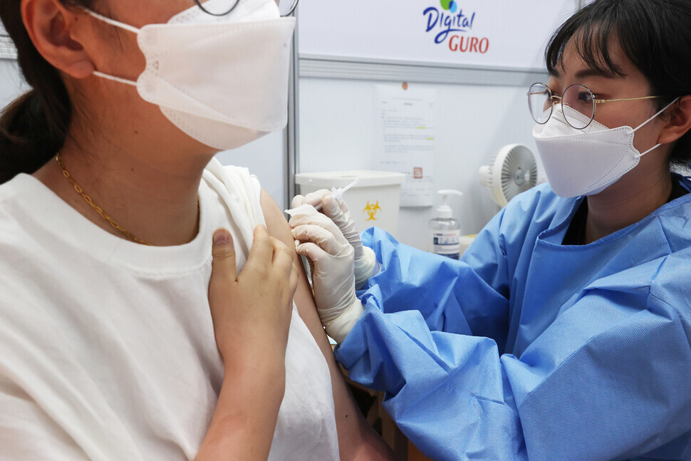 A health worker administers a dose of COVID-19 vaccine to a woman at a vaccination center in Seoul on Thursday. (Yonhap News)