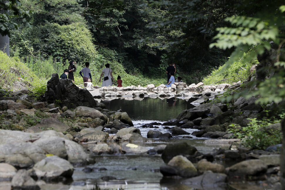 People avoid the heat at a stream in Yongin, Gyeonggi Province, on Tuesday. (Lee Jeong-a/The Hankyoreh)